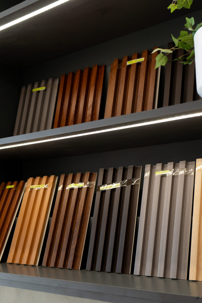Wall-mounted cladding sample boards arranged inside the Flame & Finish showroom.